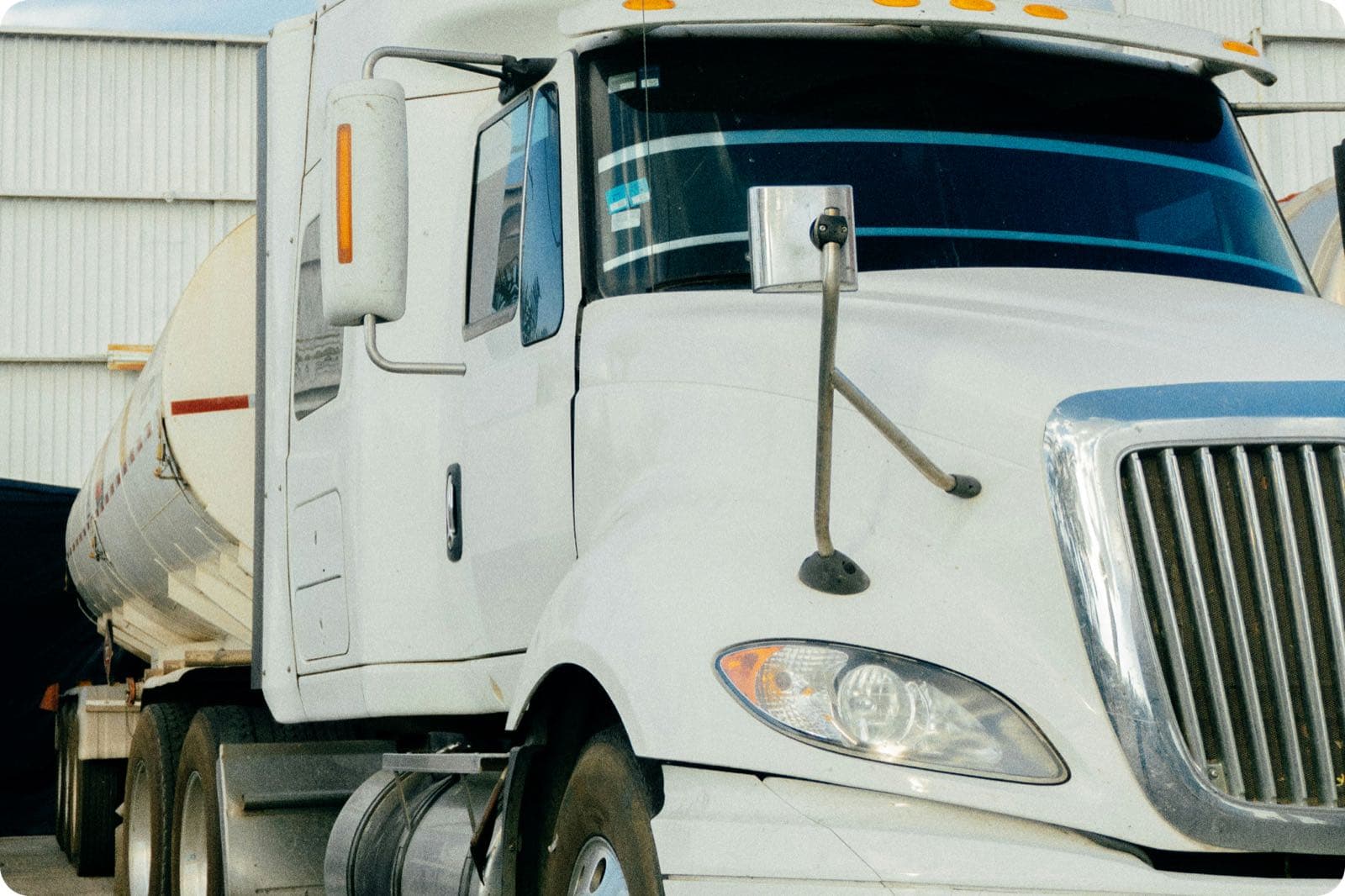 Close-up of a white tanker truck cab hauling a liquid tanker trailer at a loading dock