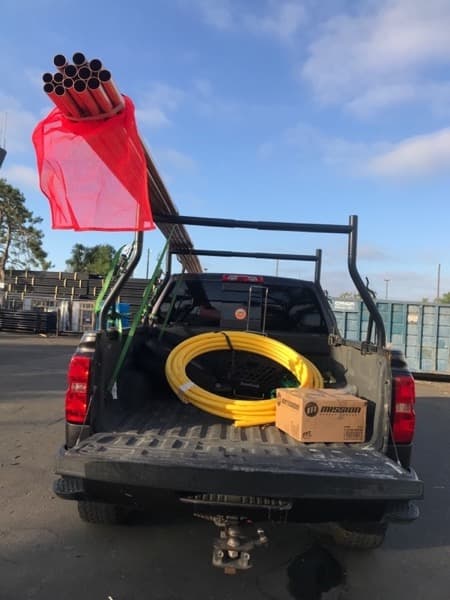 Curri flatbed picking up heavy equipment from a yard